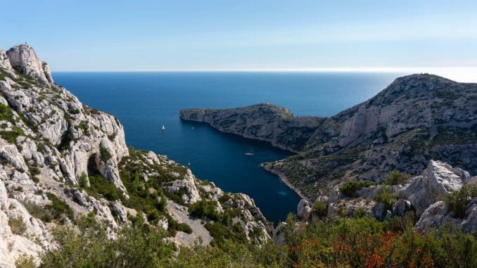 green and brown mountain beside blue sea under blue sky during daytime