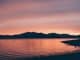 silhouette of mountain near body of water during sunset